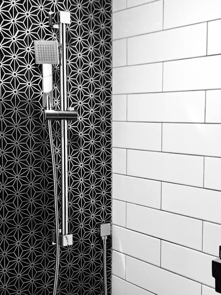 Walk-in shower with black geometric and white subway tile